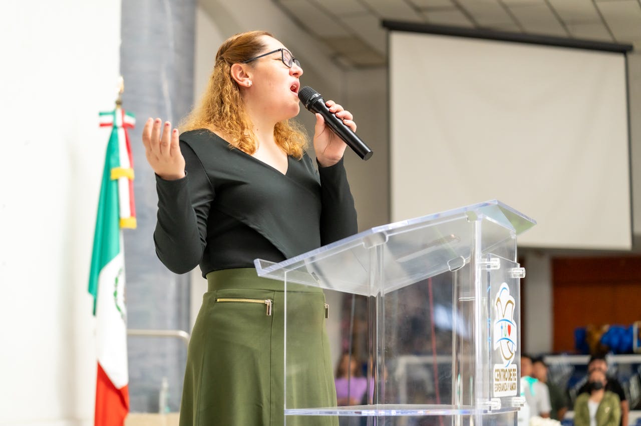A woman speaks passionately at an event in Ciudad de México, indoors.