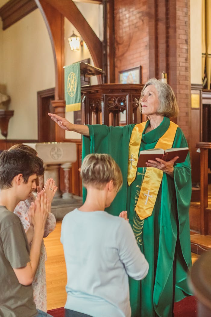 An elderly priest leads a prayer with parishioners in a church setting, exuding reverence and tradition.